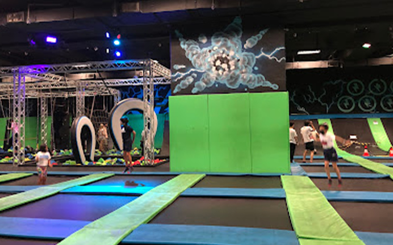 Indoor free trampoline area with professional modular trampolines and bright orange padded borders in a family-friendly Spanish park