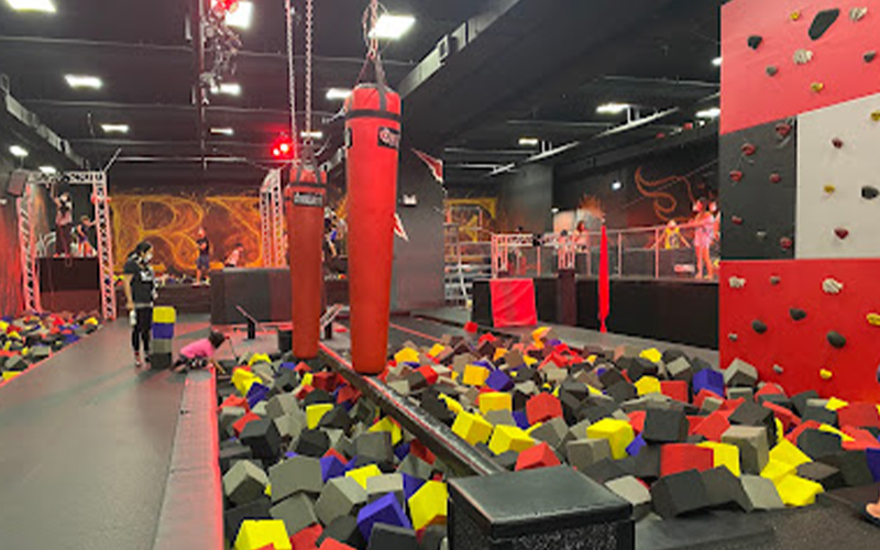 Ninja obstacle course combining trampolines, balance beams, and monkey bars in a Valencia indoor park