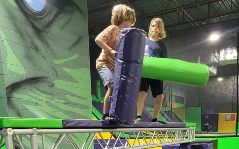 Trampoline balance beam with non-slip surface and safety rails in an indoor trampoline park