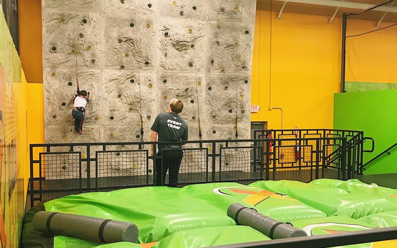 Climbing wall set inside the trampoline park for thrill-seekers