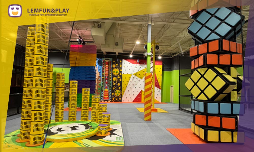 An engaging indoor rock climbing wall positioned safely over a foam pit, integrated seamlessly with commercial trampoline equipment.