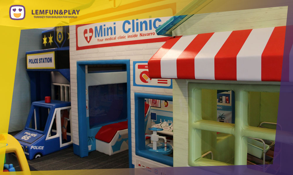Toddler-safe soft play area with macaron-shaped foam climbing blocks and licorice-themed tunnels in a candy theme.