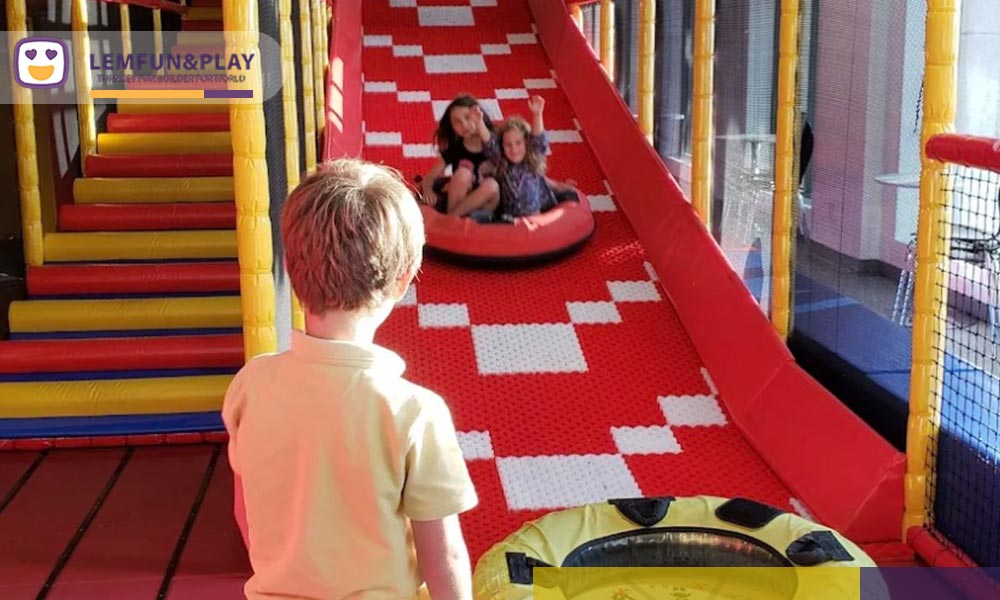 A bespoke pink donuts slide with a high-gloss finish, designed as a central attraction for the candy themed kids indoor game zone for sale, featuring ergonomic curves and a 