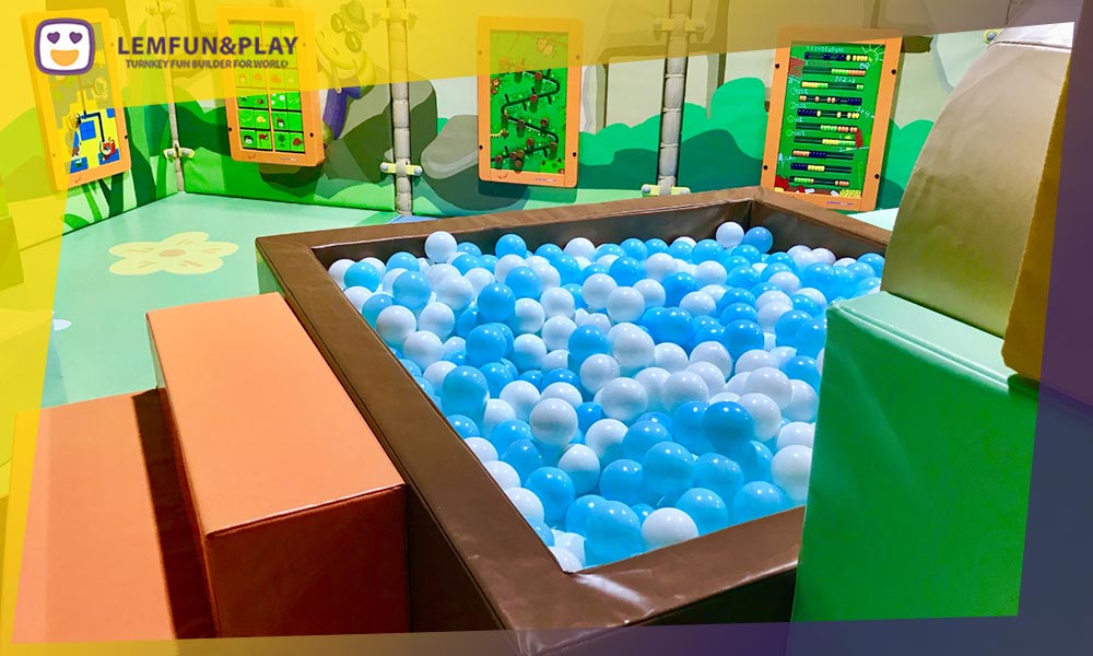 Large kids ball pool filled with jungle-toned balls, connected to a custom slide game set for a complete jungle styled kids indoor play area for business.