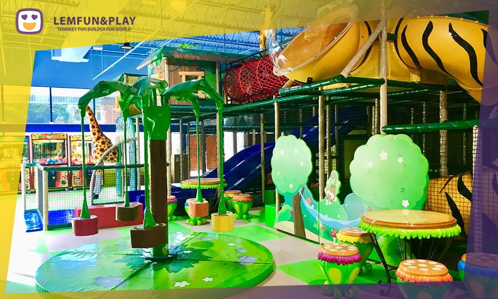 A motorized coconut-tree themed kids merry-go-round designed for safe, soft play within a jungle styled kids indoor play area for business.