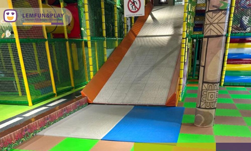 Thrilling kids donuts slide featuring a specialized high-slip artificial turf ramp engineered to mimic a steep jungle river canyon.
