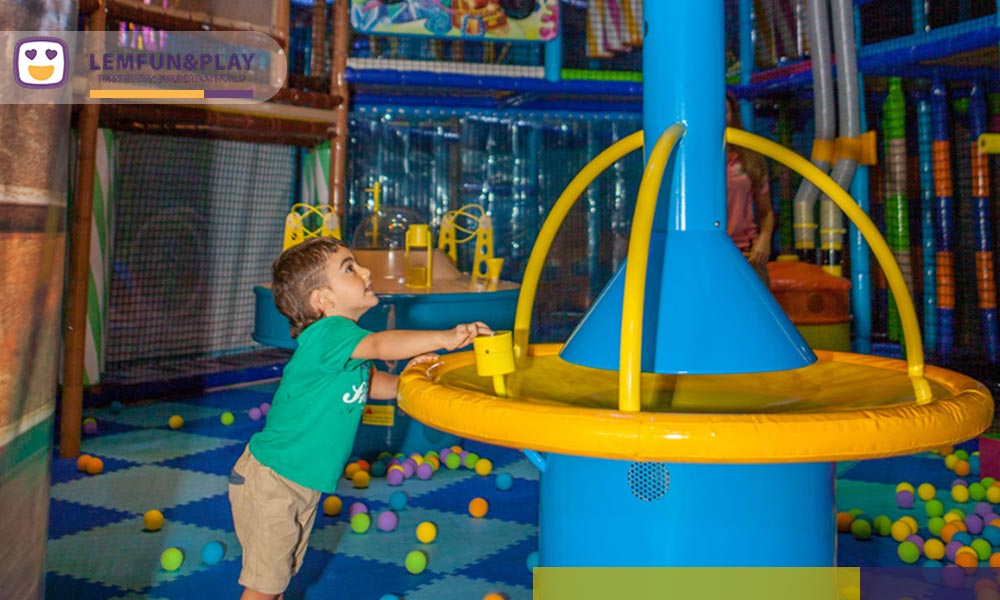 Engaging interactive ball game machine integrated seamlessly into the multi-level jungle maze play area to enhance play functionality.