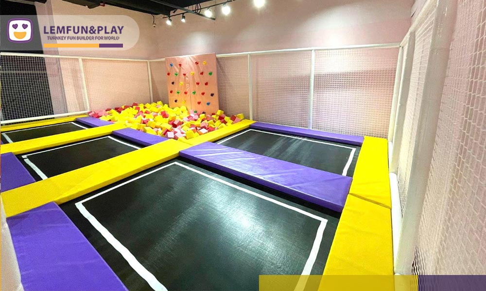 Commercial kids trampoline area with safety padding and toddler climbing wall at Funtopia