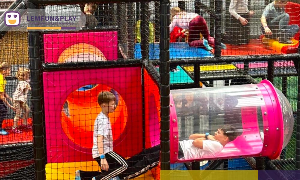 Children exploring transparent pink observation tubes and obstacle crawl tunnels inside the candy-themed maze framework.