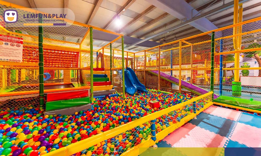 Early childhood toddler soft play area with colorful caterpillar tunnel and checkerboard padded flooring at Europark Indoor in Vias, France.