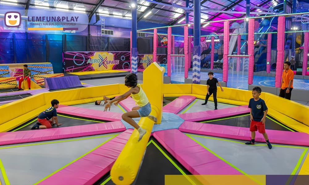 Interactive Wipe Out trampoline sweeper arm game with neon safety padding for teenagers and adults at Aeroxspace Adventure.